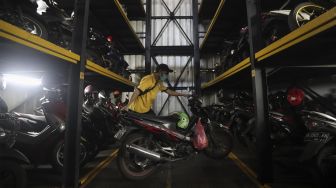 Pekerja menurunkan sepeda motor di Soul Parking, Kebon Kacang, Jakarta, Senin (24/1/2022). [Suara.com/Angga Budhiyanto]