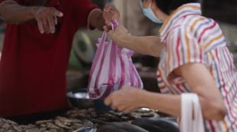 Pedagang ikan bandeng melayani pembeli di kawasan Petak Sembilan, Glodok, Jakarta, Senin (24/1/2022). [Suara.com/Angga Budhiyanto]