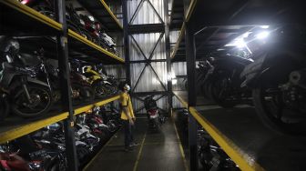Pekerja menurunkan sepeda motor di Soul Parking, Kebon Kacang, Jakarta, Senin (24/1/2022). [Suara.com/Angga Budhiyanto]