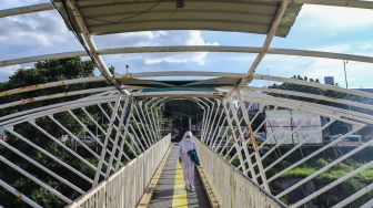 Warga melintas di Jembatan Penyeberangan Orang (JPO) Jayakarta di Menteng, Jakarta Pusat, Senin (24/1/2022). [Suara.com/Alfian Winanto]