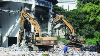 Alat berat meruntuhkan bangunan museum Telekomunikasi yang akan direnovasi di TMII, Jakarta, Senin (24/1/2022).  [Suara.com/Septian]