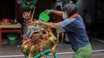 Petugas membersihkan patung di Vihara Amurva Bhumi, Jakarta, Selasa (25/1/2022). [Suara.com/Septian]