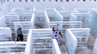 Orang-orang berkostum ksatria berbaju besi dan Olaf dari film &quot;Frozen&quot; berjalan di Ice Palace Maze, Stillwater, Minnesota, Amerika Serikat, pada (21/1/2022). [KEREM YUCEL / AFP]