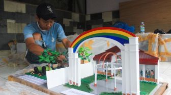 Perajin menyelesaikan pembuatan maket di Maket Diorama, Depok, Jawa Barat, Rabu (26/1/2022).  [Suara.com/Septian]

