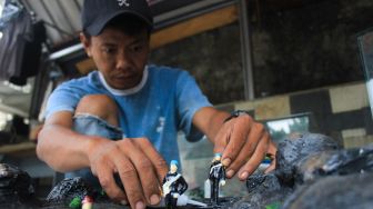 Perajin menyelesaikan pembuatan maket di Maket Diorama, Depok, Jawa Barat, Rabu (26/1/2022).  [Suara.com/Septian]
