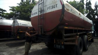 Pekerja memeriksa truk tangki minyak goreng yang sudah tidak beroperasi di kantor distributor minyak goreng SGT, Desa Dampyak, Kabupaten Tegal, Jawa Tengah, Jumat (28/1/2022). [ANTARA FOTO/Oky Lukmansyah]
