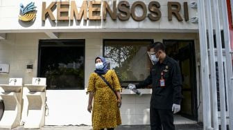 Petugas keamanan menyemprotkan cairan disinfektan pada pedagang yang berdagang di depan Kantor Pusat Kementerian Sosial (Kemensos), Jakarta, Jumat (28/1/2022). [ANTARA FOTO/M Risyal Hidayat]