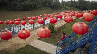 Warga melintas di pinggir Sungai Bengawan Solo yang dihiasi lampion menyambut Tahun Baru Imlek 2022 di Taman Sunan Jogo Kali, Pucang Sawit, Solo, Jawa Tengah, Kamis (27/1/2022). [ANTARA FOTO/Mohammad Ayudha]