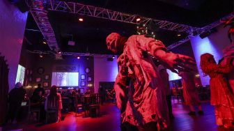 Aktor berkostum zombie memeriahkan suasana di restoran &quot;Shadows&quot; bertema horor di kota hiburan Boulevard, Riyadh, Arab Saudi, pada (19/1/2022). [FAYEZ NURELDINE / AFP]