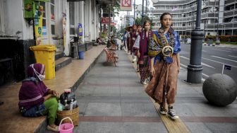 Sejumlah model memeragakan busana dari kain khas nusantara saat penampilan fesyen di ruang publik di Jalan Asia Afrika, Bandung, Jawa Barat, Jumat (28/1/2022). [ANTARA FOTO/Raisan Al Farisi]