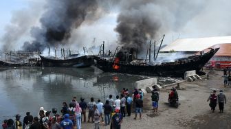 Sejumlah warga melihat kapal ikan yang terbakar di Pelabuhan Tegal, Jawa Tengah, Sabtu (29/1/2022). [ANTARA FOTO/Oky Lukmansyah]