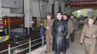 Pemimpin Korea Utara Kim Jong Un (tengah) memeriksa pabrik amunisi yang memproduksi sistem senjata utama di lokasi yang dirahasiakan, dirilis oleh Kantor Berita Pusat Korea (KCNA) Resmi Korea Utara pada (28/1/2022). [STR / AFP / KCNA VIA KNS]