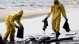 Pekerja membersihkan tumpahan minyak mentah di Pantai Mae Ram Phueng, menyusul tumpahan yang disebabkan oleh kebocoran pipa bawah laut milik Star Petroleum Refining Public Company Limited (SPRC) di Rayong, Thailand, Sabtu (29/1/2022). [JACK TAYLOR / AFP]