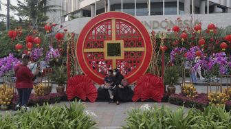 Warga berfoto di depan ornamen dengan nuansa Imlek yang di pasang di sekitar Bundaran Hotel Indonesia (HI), Jakarta, Sabtu (29/1/2022). [Suara.com/Angga Budhiyanto]