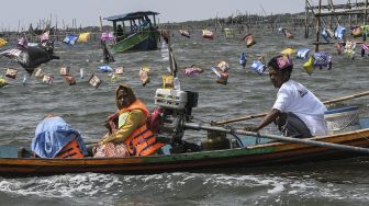 Nelayan dan warga menggunakan kapal menuju lokasi melarung (menghanyutkan) sesaji di laut Tarumajaya, Kabupaten Bekasi, Jawa Barat, Jumat (28/1/2022). [ANTARA FOTO/Fakhri Hermansyah]