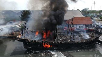 Petugas pemadam kebakaran menyemprotkan air pada kapal nelayan yang terbakar di Pelabuhan Tegal, Jawa Tengah, Sabtu (29/1/2022). [ANTARA FOTO/Oky Lukmansyah]
