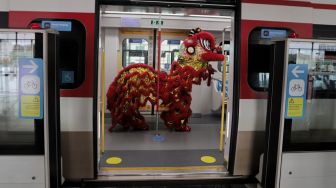 Barongsai menghibur penumpang di dalam gerbong LRT, Jakarta, Selasa (1/2/2022). [Suara.com/Angga Budhiyanto]