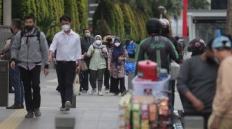 Sejumlah pekerja berjalan di trotoar kawasan Sudirman, Jakarta, Rabu (2/2/2022). [Suara.com/Angga Budhiyanto]