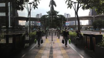 Pekerja berjalan di trotoar kawasan Sudirman, Jakarta, Rabu (2/2/2022). [Suara.com/Angga Budhiyanto]