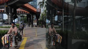 Pedagang keliling melintas di trotoar kawasan Sudirman, Jakarta, Rabu (2/2/2022). [Suara.com/Angga Budhiyanto]