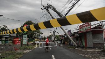 Warga berada di dekat tiang listrik yang roboh di Banguntapan, Bantul, DI Yogyakarta, Rabu (2/2/2022). ANTARA FOTO/Hendra Nurdiyansyah
