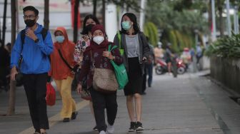Sejumlah pekerja berjalan di trotoar kawasan Sudirman, Jakarta, Rabu (2/2/2022). [Suara.com/Angga Budhiyanto]