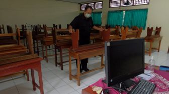 Petugas merapikan kursi di ruang kelas SMP Negeri 3 Denpasar, Bali, Jumat (4/2/2022). ANTARA FOTO/Nyoman Hendra Wibowo
