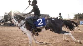 Seorang Joki muda saat mengikuti pertandingan balap kuda di Kota Ouagadougou, Burkina Faso, Senin (30/1/2022). [Photo by JOHN WESSELS / AFP]