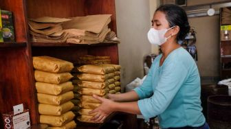 Seorang pekerja membungkus kopi di Toko Kopi Sari Murni, Jatinegara, Jakarta Timur, Sabtu (5/2/2022). [Suara.com/Alfian Winanto]