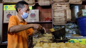 Seorang pekerja memasukan kopi ke bungkusnya di Toko Kopi Sari Murni, Jatinegara, Jakarta Timur, Sabtu (5/2/2022). [Suara.com/Alfian Winanto]