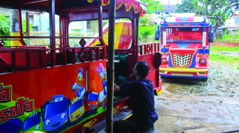 Pekerja menyelesaikan pembuatan odong-odong di Pondok Aren, Tangerang Selatan, Banten, Minggu (6/2/2022).  [Suara.com/Septian]
