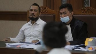 Terdakwa yang juga musisi I Gede Ari Astina atau Jerinx Superman is Dead (SID) (kiri) menjalani sidang lanjutan kasus pengancaman melalui media elektronik pada Adam Deni dengan agenda mendengarkan keterangan dari saksi ahli di Pengadilan Negeri (PN) Jakarta Pusat, Jakarta, Senin (7/2/2022). [Suara.com/Angga Budhiyanto]