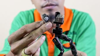 Seto Krisna Putra saat membuat miniatur robot dari limbah korek gas di Pinang Ranti, Jakarta Timur, Kamis (10/2/2022). [Suara.com/Alfian Winanto]