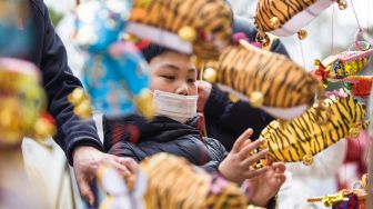 Seorang anak melihat-lihat lentera menjelang festival lampion di Nanjing, China, Kamis (10/2/2022). [STR/AFP]