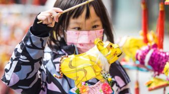 Seorang anak memegang lentera menjelang festival lampion di Nanjing, China, Kamis (10/2/2022). [STR/AFP]