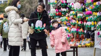 Warga berbelanja lentera menjelang festival lampion di Nanjing, China, Kamis (10/2/2022). [STR/AFP]