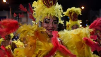 Para penari yang dikenal sebagai 'komparsa' bersaing dengan dengan memainkan musik dan tarian tradisional 'candombe' saat festival 'Las Llamadas' di Montevideo, Uruguay, Kamis (10/2/2022). [PABLO PORCIUNCULA / AFP]