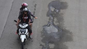 Kendaraan bermotor melewati jalan berlubang di Jalan Rasuna Said, Kuningan, Jakarta, Minggu (13/2/2022). [Suara.com/Angga Budhiyanto]