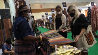 Pengunjung melihat koleksi kain tradisional saat Pameran Adiwastra Nusantara di Jakarta Convention Center (JCC), Jakarta, Minggu (13/2/2022). [Suara.com/Angga Budhiyanto]