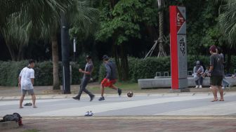 Warga bermain sepak bola di kompleks Gelora Bung Karno, Senayan, Jakarta, Minggu (13/2/2022). [Suara.com/Angga Budhiyanto]