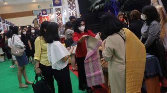 Pengunjung melihat koleksi kain tradisional saat Pameran Adiwastra Nusantara di Jakarta Convention Center (JCC), Jakarta, Minggu (13/2/2022). [Suara.com/Angga Budhiyanto]