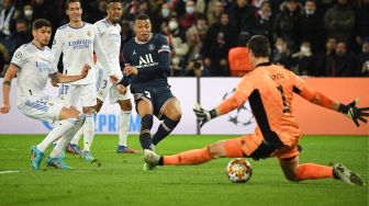 Pemain depan Paris Saint-Germain Kylian Mbappe (tengah) menembak dan mencetak gol selama pertandingan sepak bola leg pertama babak 16 besar Liga Champions antara Paris Saint-Germain (PSG) melawan Real Madrid di Stadion Parc des Princes, Rabu (16/2/2022) dini hari WIB. 
Alain JOCARD / AFP
