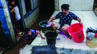 Warga permukiman kebon pala berkativitas saat banjir di Kampung Melayu, Jatinegara, Jakarta Timur, Kamis (17/2/2022). [Suara.com/Septian]