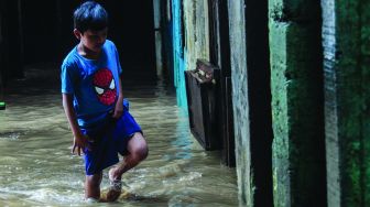 Warga permukiman kebon pala berkativitas saat banjir di Kampung Melayu, Jatinegara, Jakarta Timur, Kamis (17/2/2022). [Suara.com/Septian]