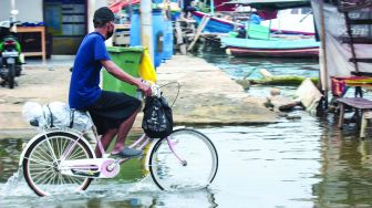 Aktivitas warga sekitar saat banjir Rob di pelabuhan Muara Angke, Jakarta Utara, Minggu (20/2/2022).  [Suara.com/Septian]