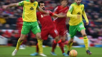 Gelandang Liverpool Mohamed Salah (tengah) bersaing dengan bek Norwich City Grant Hanley (kiri) saat pertandingan sepak bola Liga Premier Inggris antara Liverpool dan Norwich City di Stadion Anfield, Liverpool, Inggris, Sabtu (19/2/2022). [Oli SCARFF / AFP]