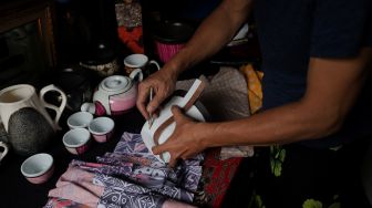 Suyono (51) menyelesaikan pembuatan batik rekat pada media pot bunga di Say Galery, Sukmajaya, Depok, Jawa Barat, Senin (21/2/2021). [Suara.com/Angga Budhiyanto]