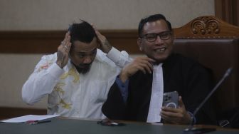 Terdakwa yang juga musisi I Gede Ari Astina atau Jerinx Superman is Dead (SID) bersiap menjalani sidang lanjutan kasus pengancaman melalui media elektronik pada Adam Deni beragendakan pleidoi atau pembacaan nota pembelaan di Pengadilan Negeri (PN) Jakarta Pusat, Jakarta, Selasa (22/2/2022). [Suara.com/Angga Budhiyanto]