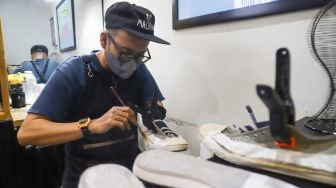 Kru membersihkan sepatu pelanggan di Cleaning Shoes Kicks Kemon, Haji Nawi, Jakarta Selatan, Rabu (23/2/2022). [Suara.com/Alfian Winanto]