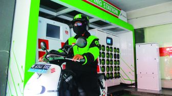 Pengemudi ojek online saat mengganti baterai sepeda motor listriknya di Swaping station, Kuningan, Jakarta, Rabu (23/2/2022).  [Suara.com/Septian]